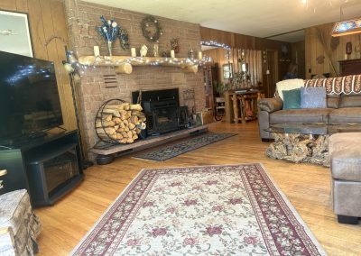 Cozy living room with bay window, comfortable seating, and glass coffee table at Travel Magick Spiritual Retreat Center main house Colorado