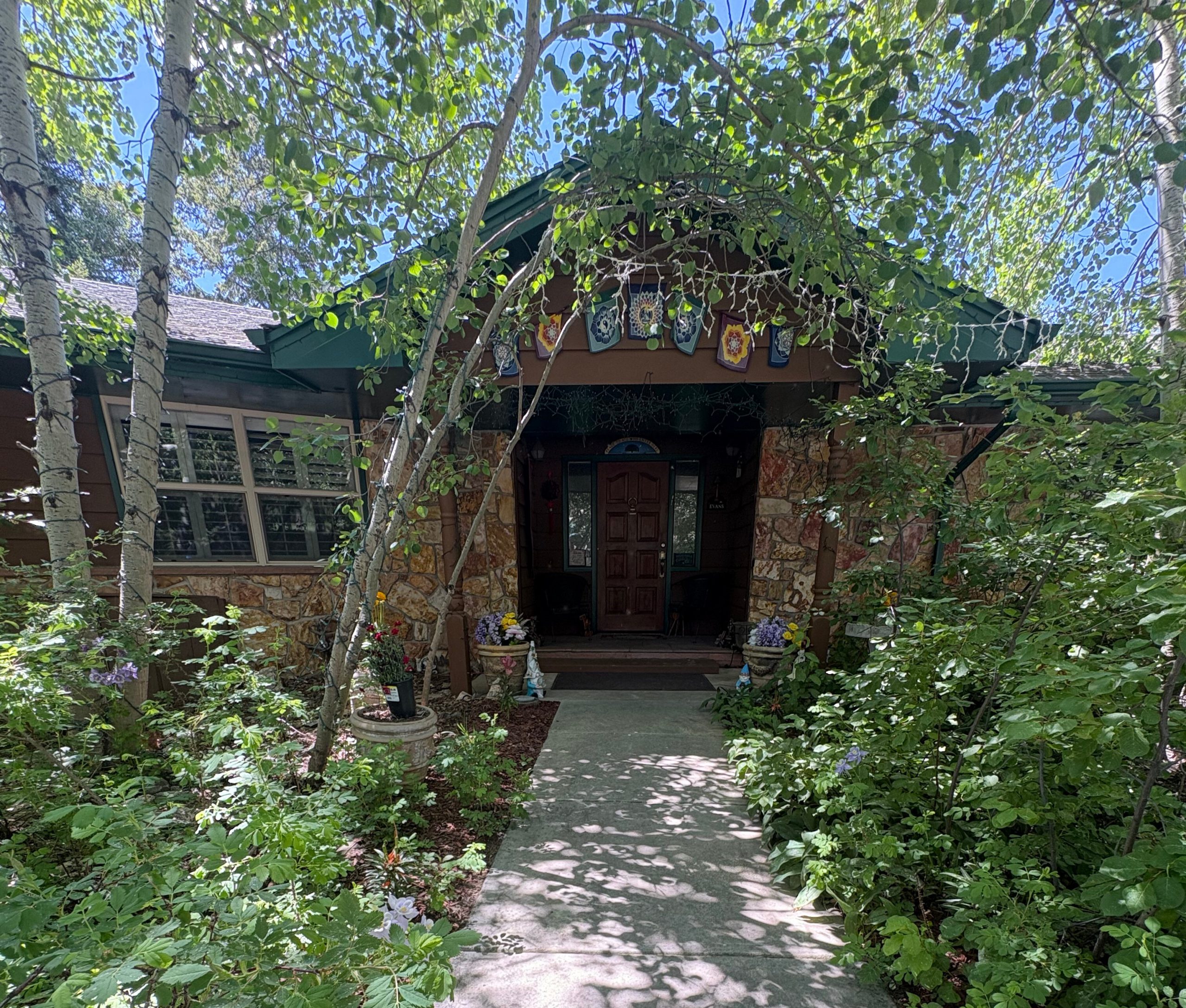 Enchanted Stone House Retreat - Travel Magick Colorado Mountain Getaway Rustic stone cottage with green metal roof surrounded by lush aspen trees and wildflowers in Colorado Rocky Mountains
