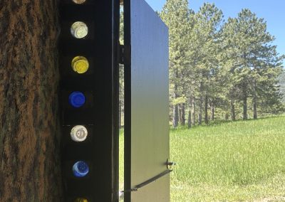 Colorful glass bottle windows in earth building wall overlooking mountain meadow at Travel Magick Spiritual Retreat Center Colorado