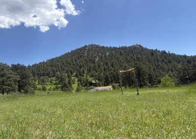 Rustic wooden arbor with flower decorations overlooking mountain meadow at Travel Magick Spiritual Retreat Center Colorado