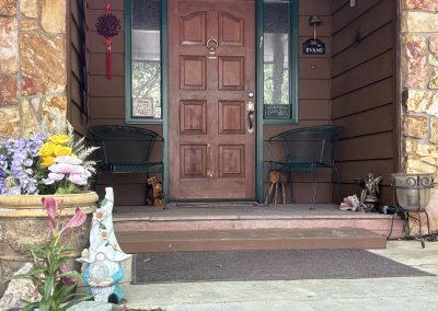Welcoming front porch entrance with stone walls, wooden door, and garden gnome at Travel Magick Spiritual Retreat Center Colorado